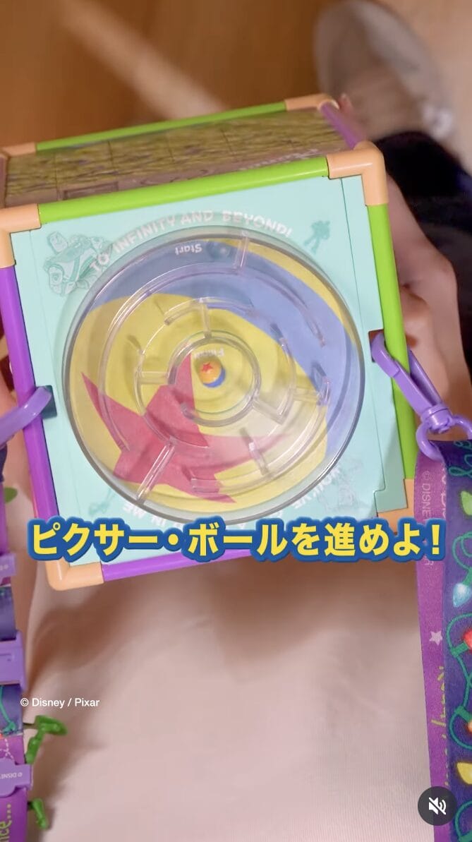 Hands holding a Toy Story-themed puzzle cube, featuring Japanese text and a Pixar ball at Tokyo Disneyland.